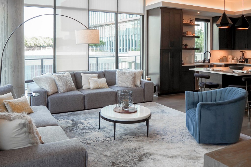 3-bedroom model living room with a gray couch and a blue chair at The Hamilton apartments in Dallas, TX