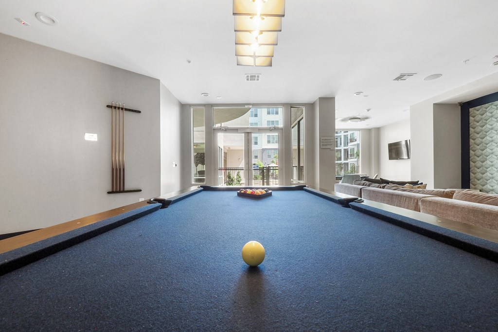 a game room with a blue pool table and a yellow ball on top of it at Harlow River Oaks in Houston, TX