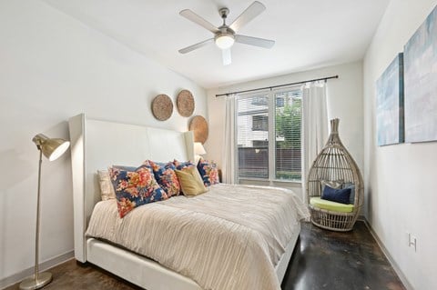 Model bedroom with a bed and a ceiling fan at Harlow River Oaks in Houston, TX