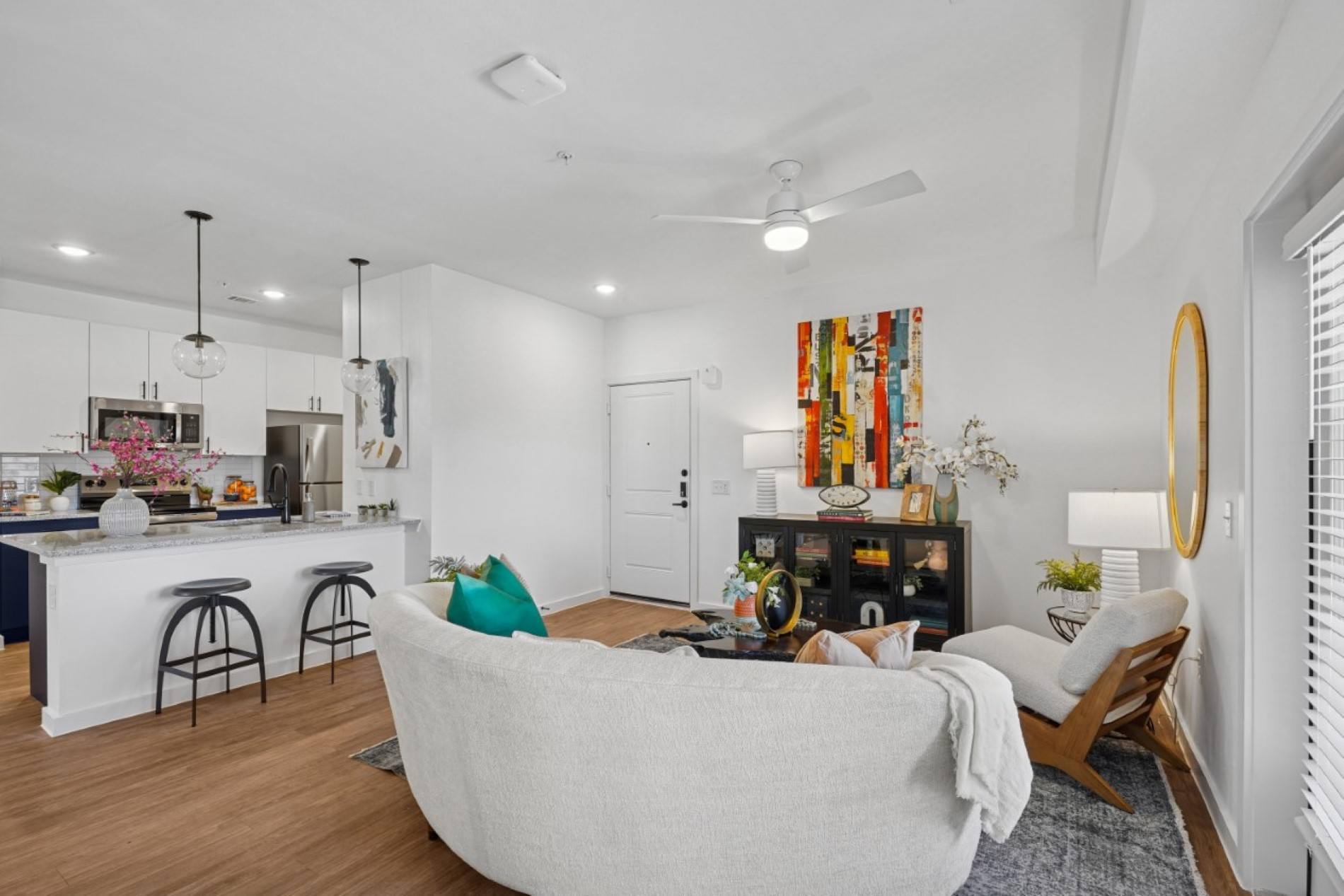 A modern living room with a white couch and a kitchen area in the background.