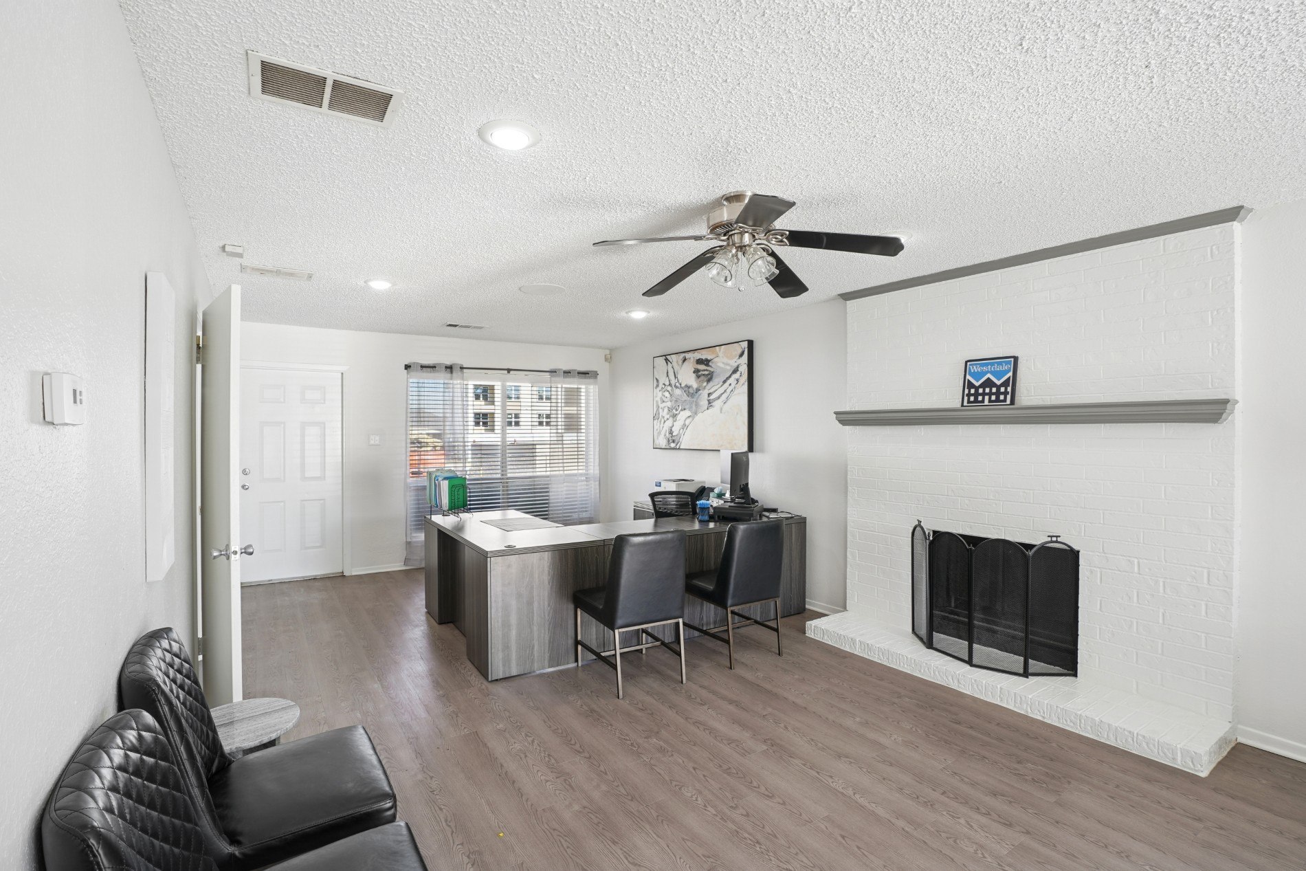 A living room with a black leather chair and a fireplace.
