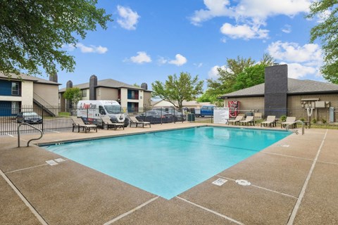 A swimming pool surrounded by a concrete deck and lounge chairs at Heritage Square Apartments in Waco, TX