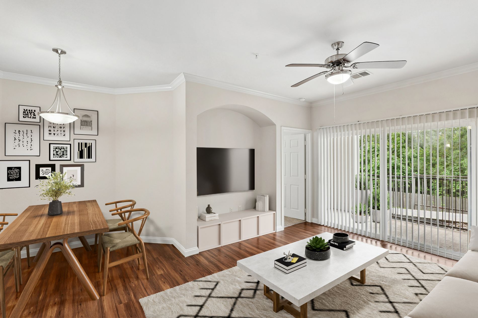 A living room with a wooden dining table and chairs, a white sofa, a television, and a ceiling fan.