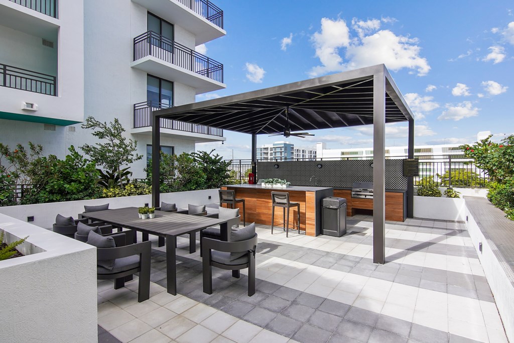 Outdoor grilling station with two BBQ grills and ample seating under a pergola at Hollywood Heights on the Boulevard Luxury Apartments in Hollywood, FL