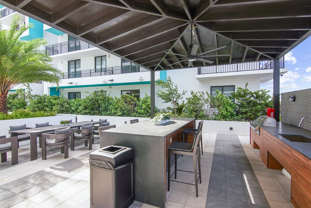 Outdoor grilling station with a table, chairs and a sink under a pavilion in our outdoor area at Hollywood Heights on the Boulevard.