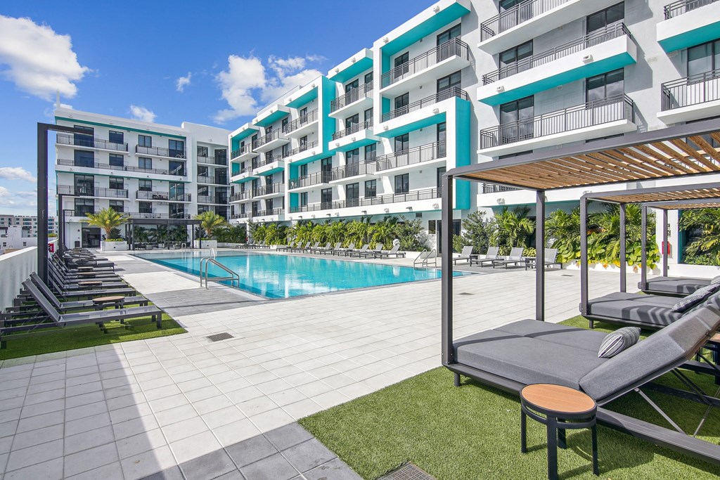 Our beautiful pool surrounded by lounge chairs and lush greenery at Hollywood Heights on the Boulevard Luxury Apartments in Hollywood, FL