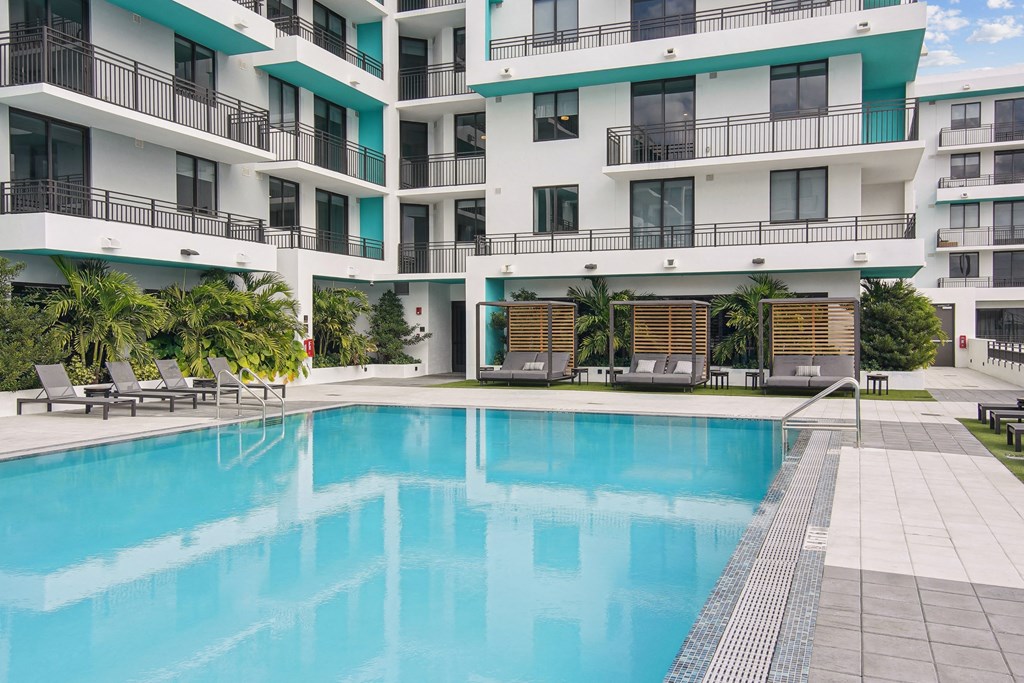 Cushioned lounge chairs and patio lounge chairs by our beautiful pool at Hollywood Heights on the Boulevard Luxury Apartments in Hollywood, FL