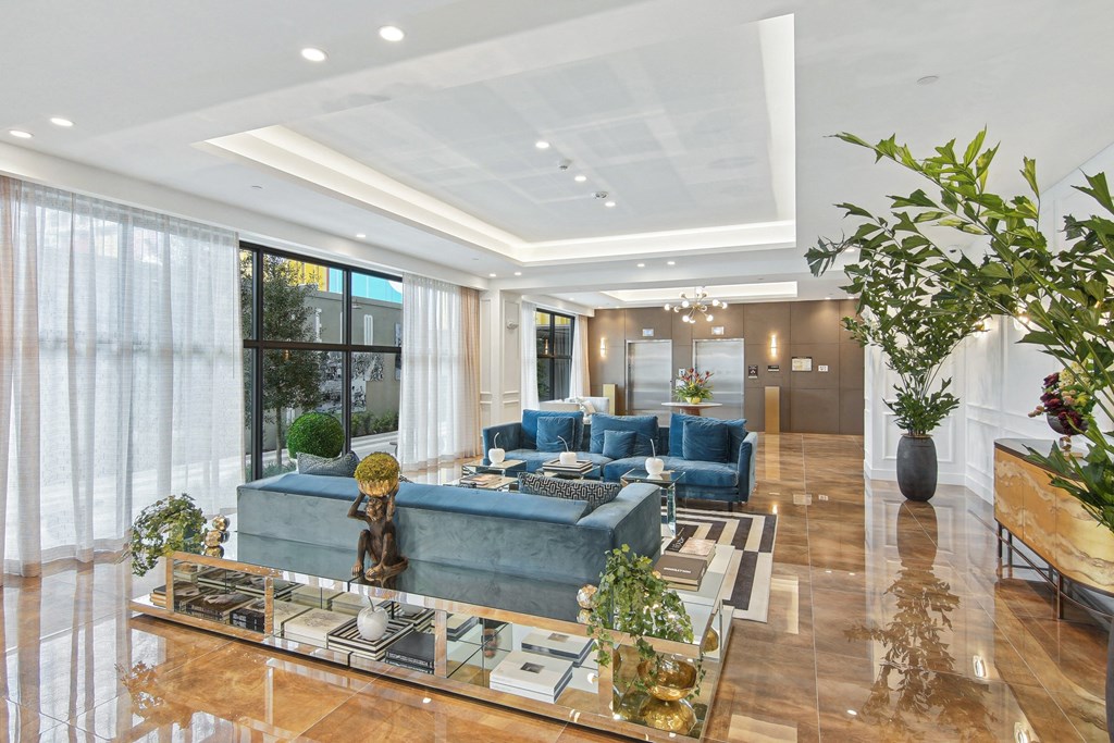 Lobby area with soft blue couches and elevators in the background at Hollywood Heights on the Boulevard Luxury Apartments in Hollywood, FL