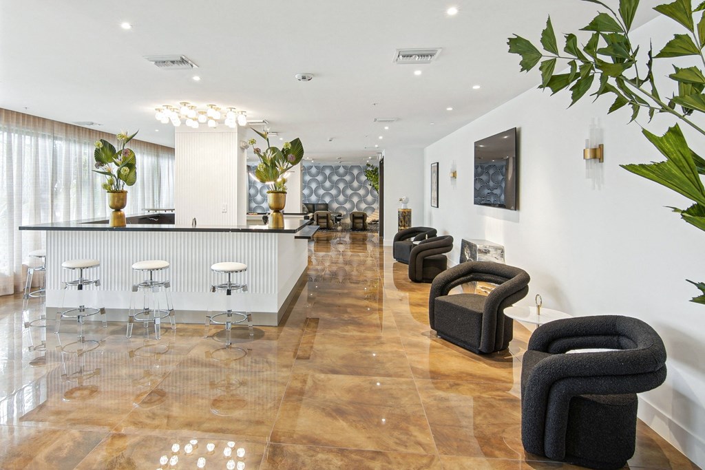 Lobby with dark grey chairs and white barstools next to our social club at Hollywood Heights on the Boulevard Luxury Apartments in Hollywood FL