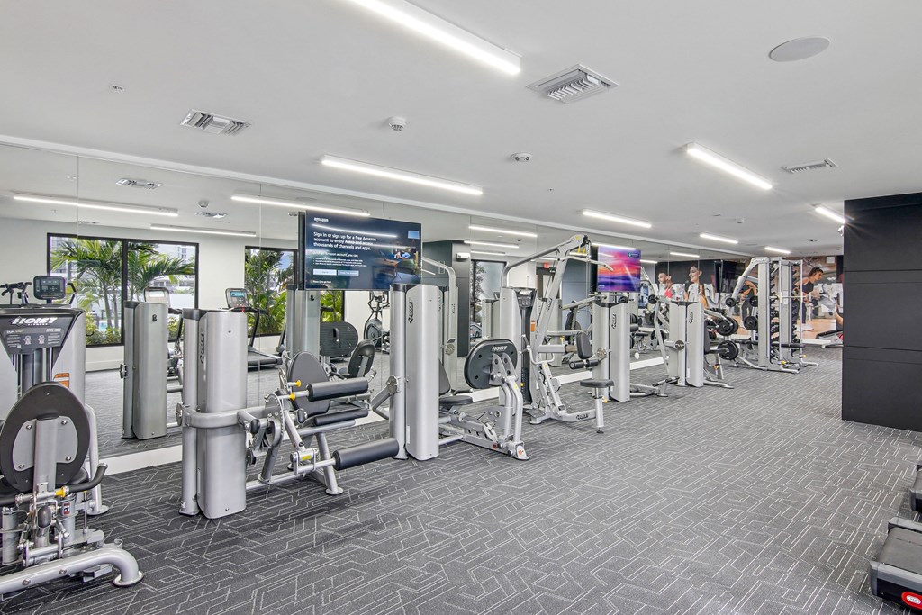 Our gym machines in our state-of-the-art fitness center with 2 large TVs and a mirror wall at Hollywood Heights on the Boulevard Luxury Apartments in Hollywood FL