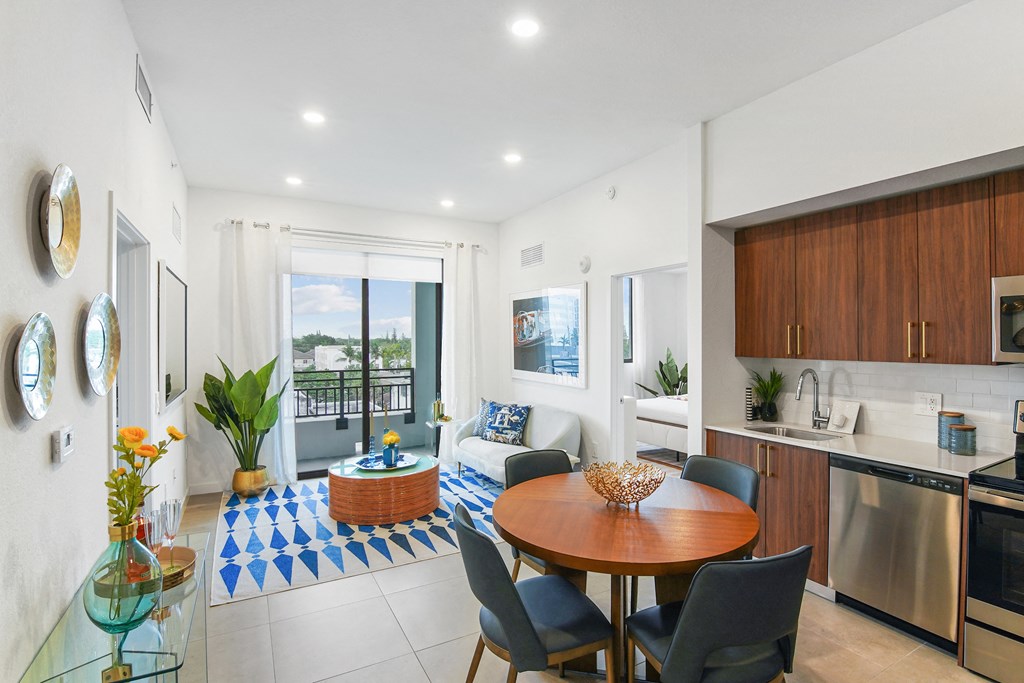Living room and modern kitchen in our 2-bedroom model with a dining table and chairs  Balcony view of Hollywood Boulevard at Hollywood Heights on the Boulevard Luxury Apartments in Hollywood, FL