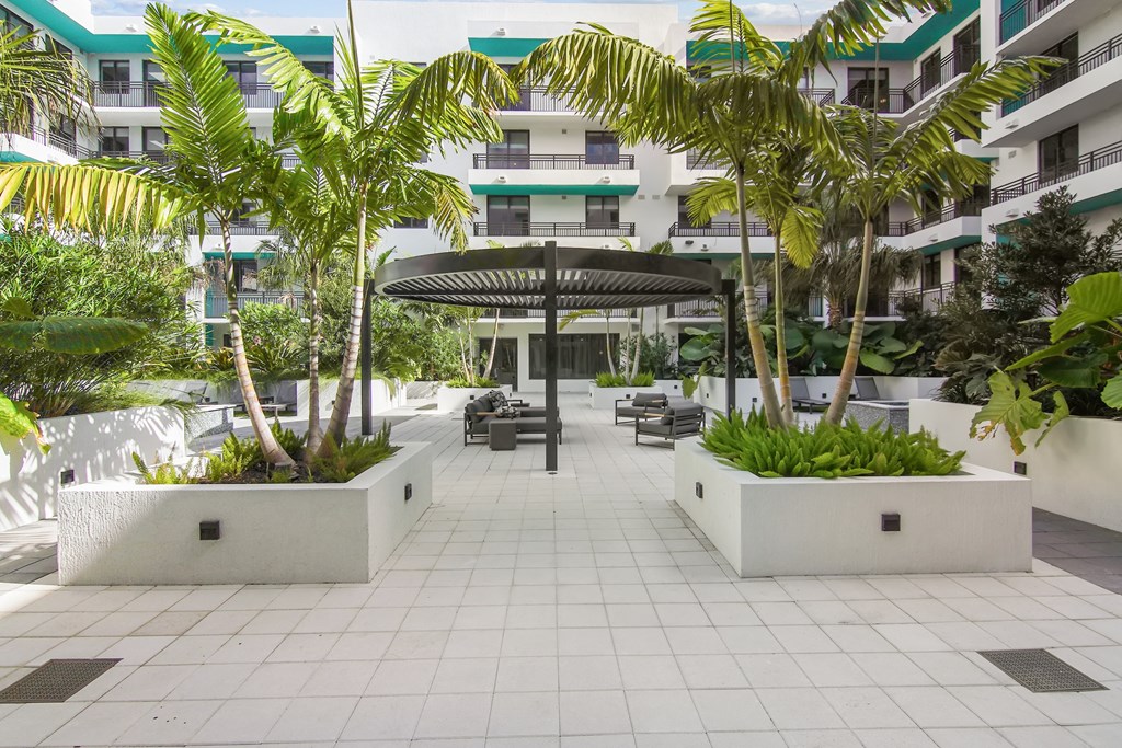Cushioned patio seating under a circular pergola surrounded by our serenity garden in our courtyard at Hollywood Heights on the Boulevard Luxury Apartments in Hollywood, FL