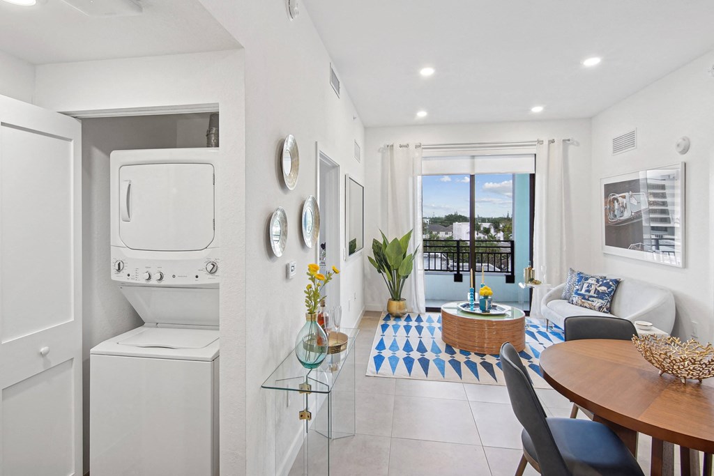 A modern living room with a dining table and chairs and a washer and dryer on the left at Hollywood Heights on the Boulevard Luxury Apartments in Hollywood, FL