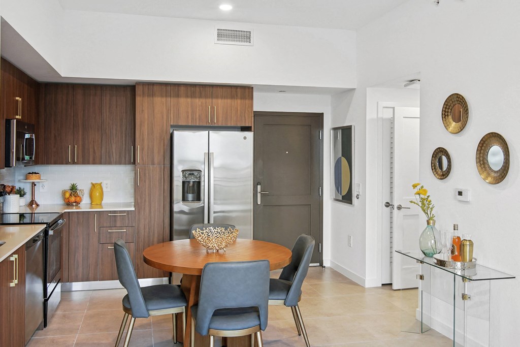 A modern kitchen with a dining table and chairs, fridge with a ice maker, stovetop, and microwave  Living room and modern kitchen in our 2-bedroom model with a dining table and chairs  Balcony view of Hollywood Boulevard at Hollywood Heights on the Boulevard Luxury Apartments in Hollywood, FL