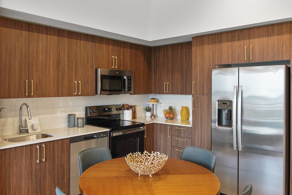 A kitchen with wooden cabinets and a stainless steel refrigerator.