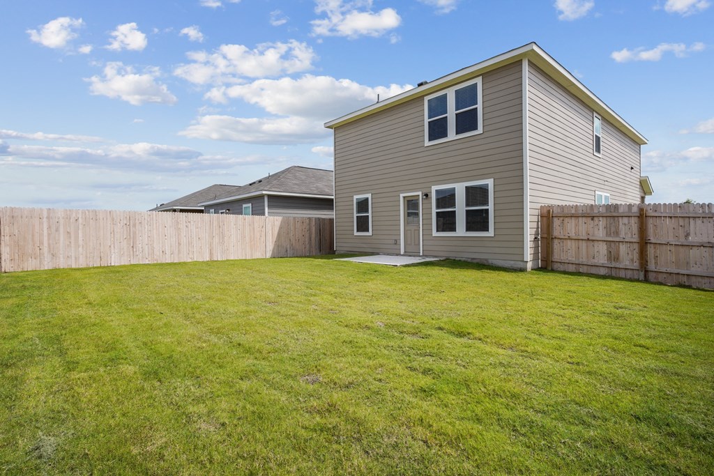 a backyard with a house and a fenced in yard at Beacon at Hymeadow, Maxwell, TX