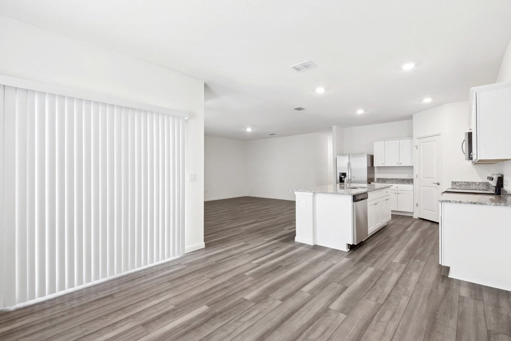 a kitchen and living room with wood floor and white walls