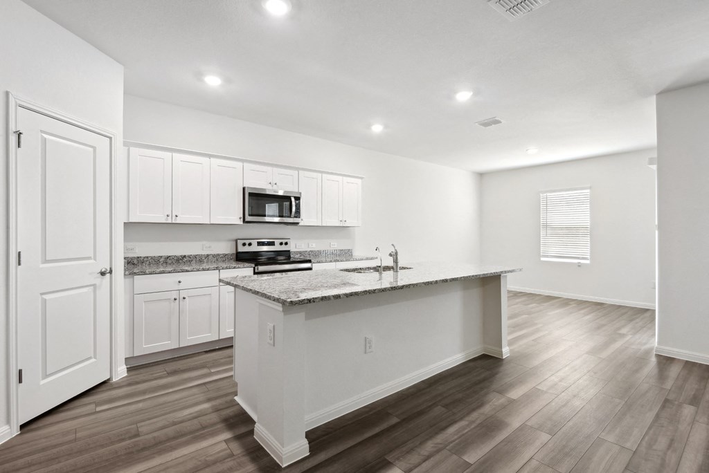 an open kitchen with white cabinets and granit counter top