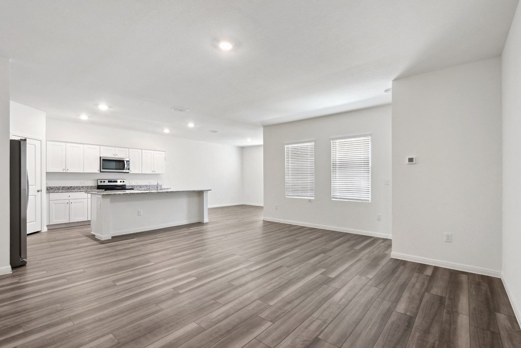 a living room and kitchen with windows and hardwod floors