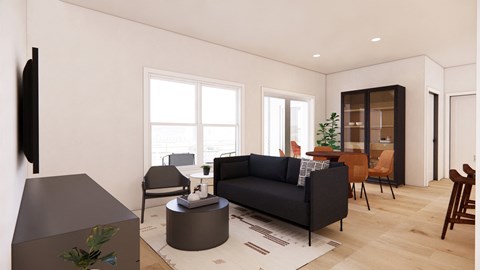A living room with a black couch, a grey ottoman, and a brown chair.