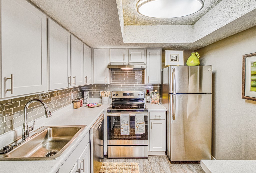 Model home renovated kitchen with stainless steel appliances and white cabinets at Hillside Creek Apartments in Austin, TX
