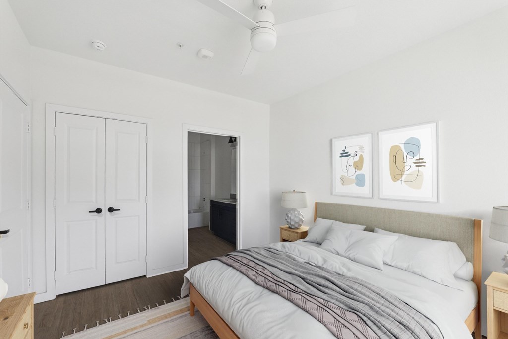A bedroom with a bed, nightstand, and two pieces of artwork on the wall.