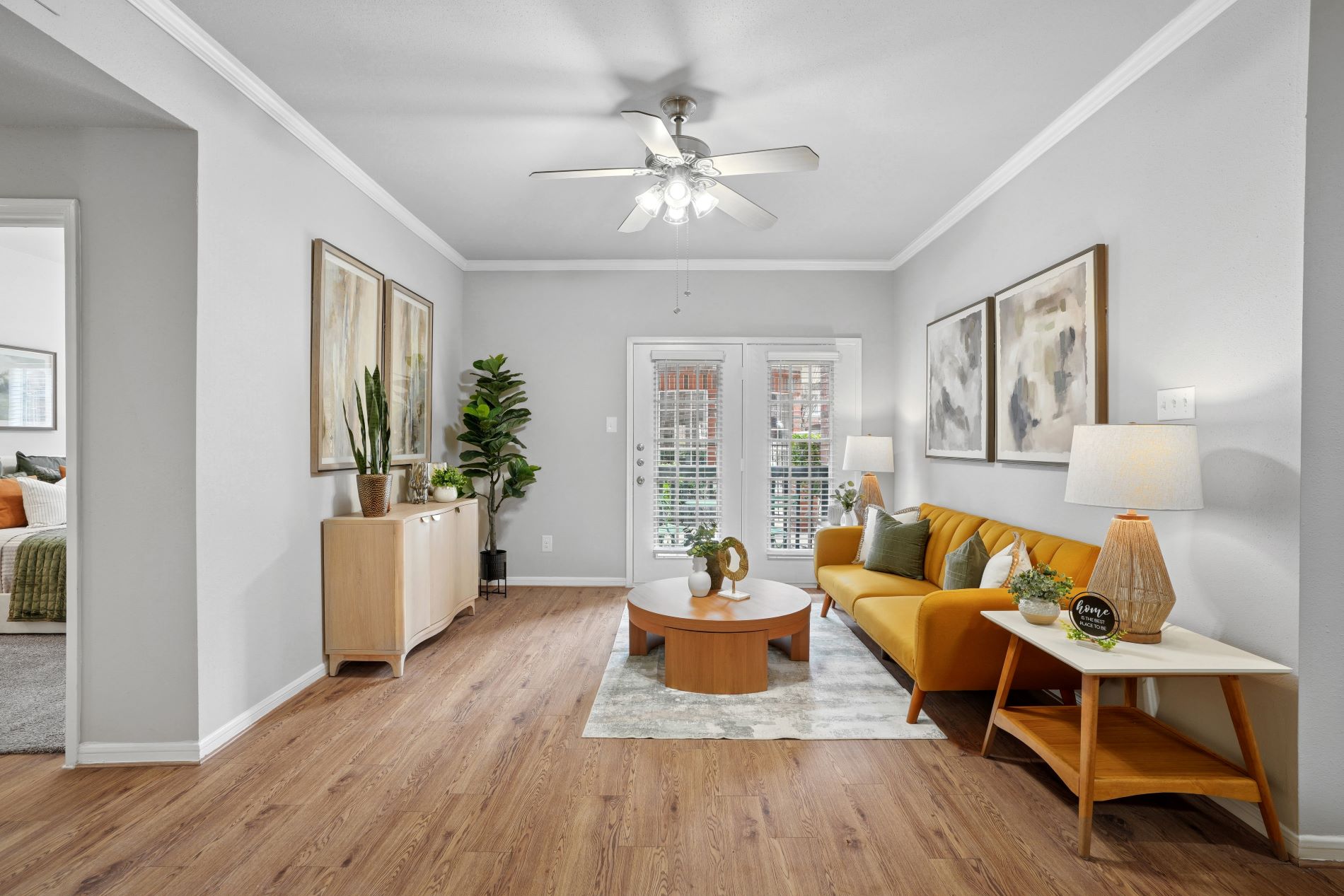 A living room with a yellow couch and wooden floors.