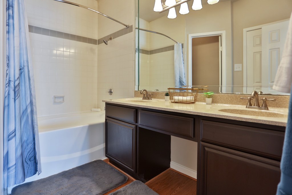 A1 bathroom with a large mirror, a sink, and a bathtub at The Inverness Apartments in Houston, TX