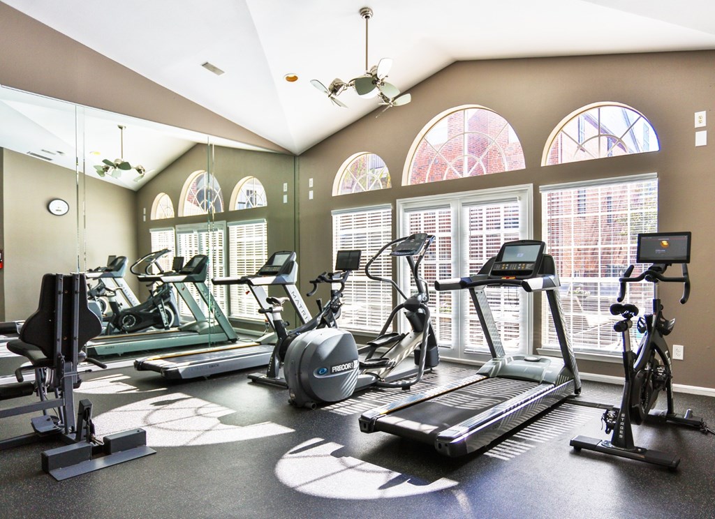 A fitness center with treadmills and elliptical machines at The Inverness Apartments in Houston, TX