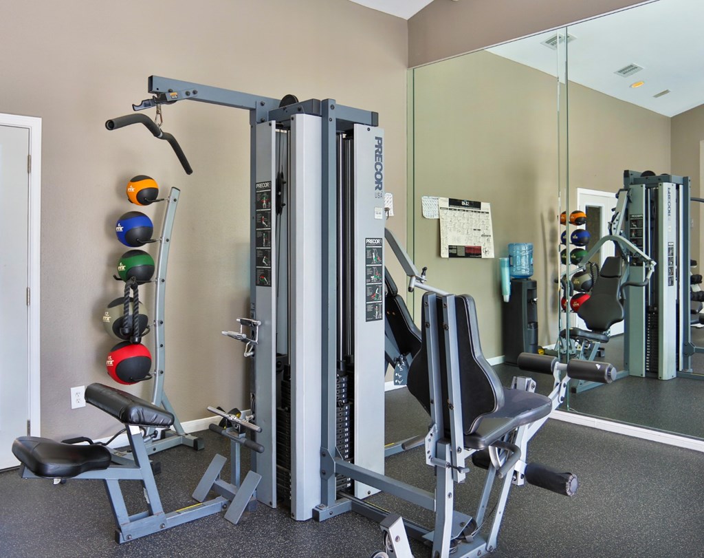 A fitness center with a variety of strength training equipment and weights at The Inverness Apartments in Houston, TX