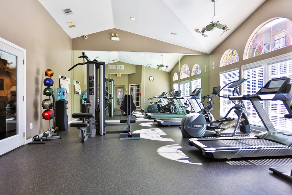 A gym with a variety of equipment including treadmills, weights, and exercise machines at The Inverness Apartments in Houston, TX