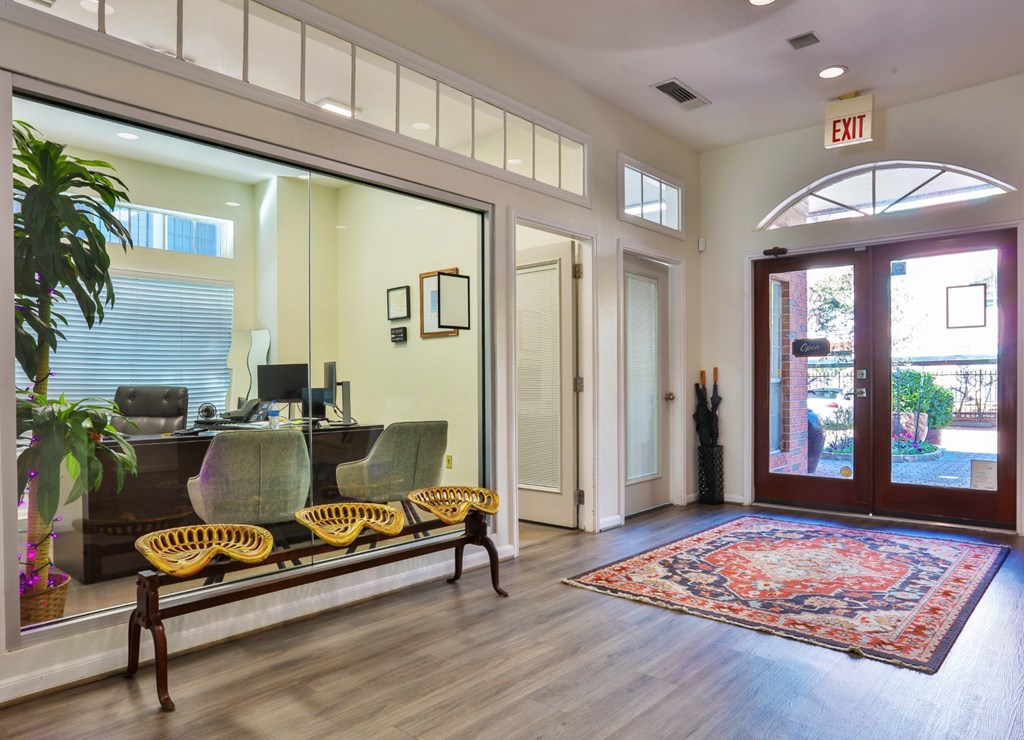 A leasing office with a bench, chairs, and a rug at The Inverness Apartments in Houston, TX