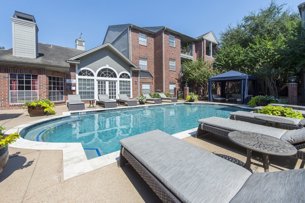 A swimming pool with lounge chairs at The Inverness Apartments in Houston, TX