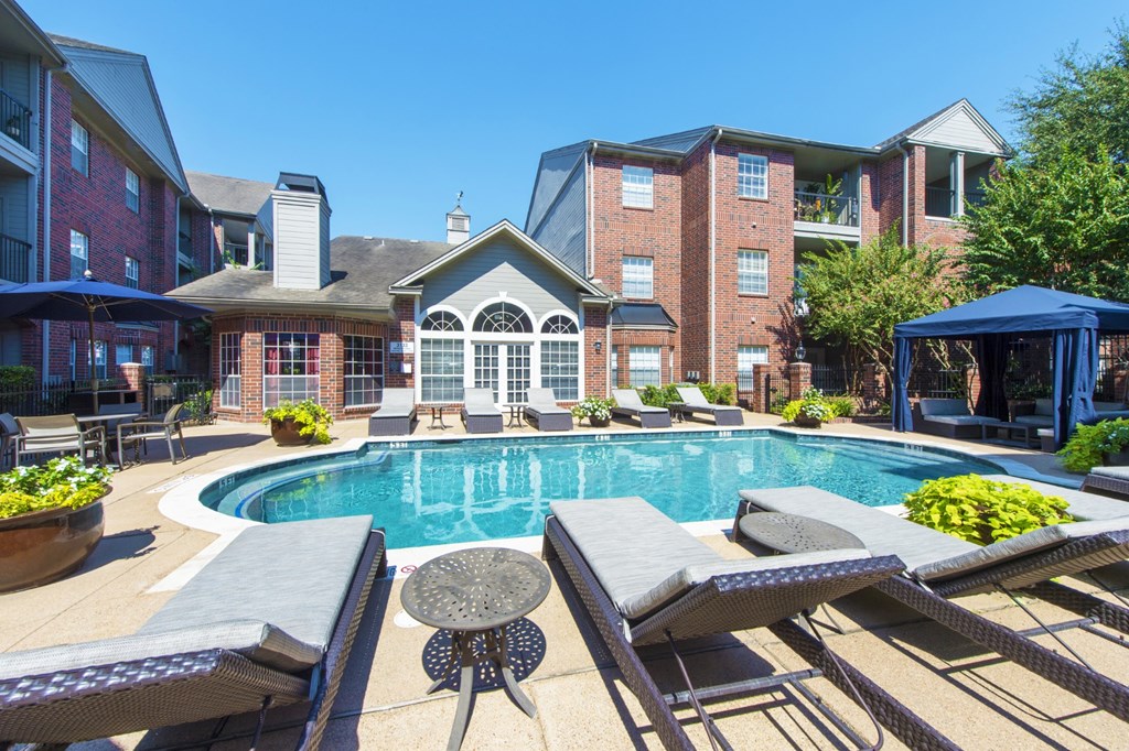 A pool surrounded by lounge chairs in front of the leasing office at The Inverness Apartments in Houston, TX