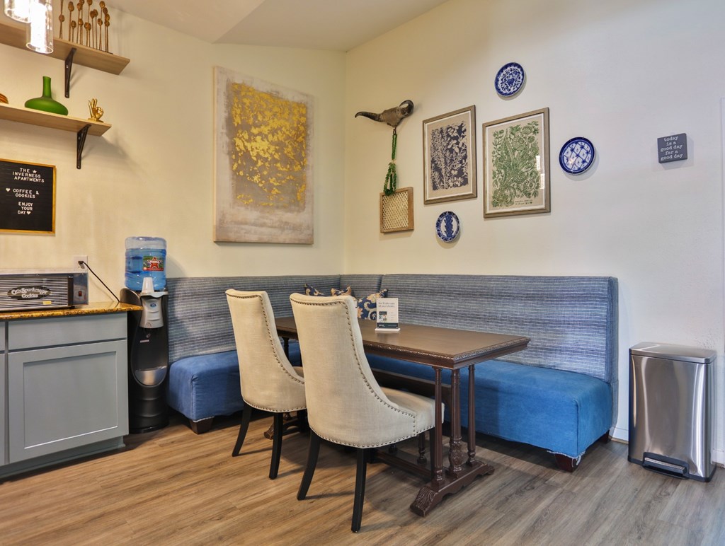 A resident lounge with a blue couch, wooden table, and two chairs at The Inverness Apartments in Houston, TX