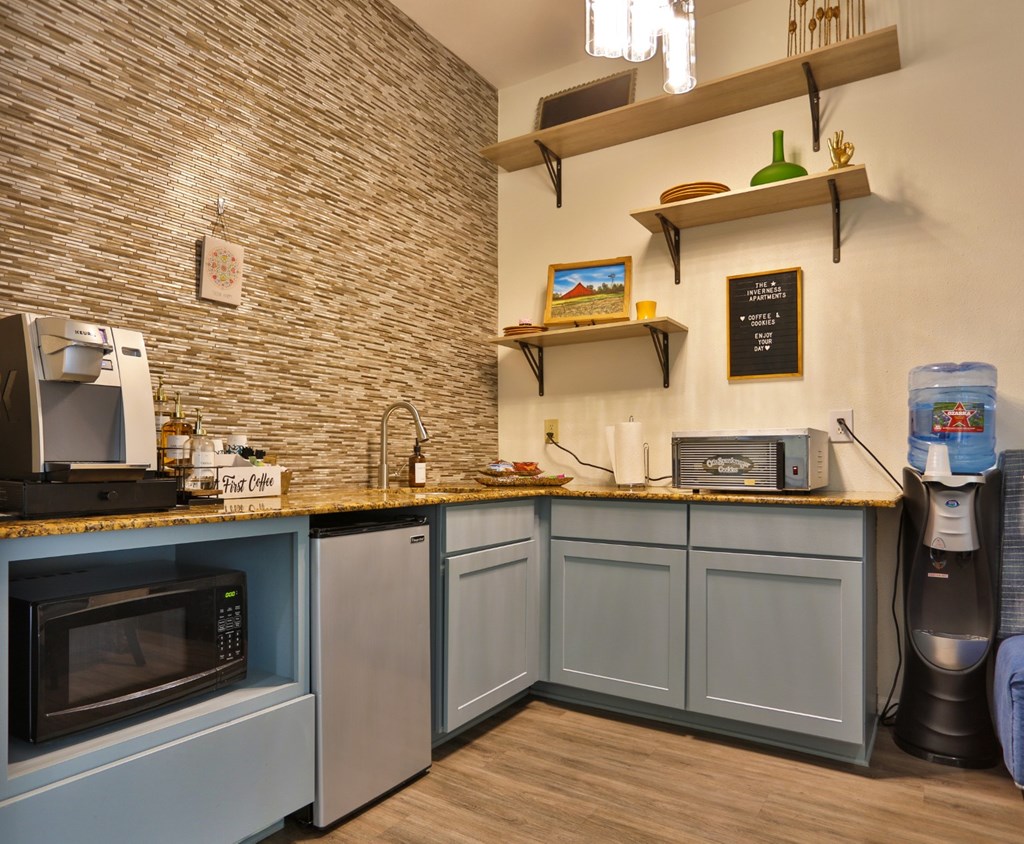 A resident lounge with a mini fridge, water cooler, microwave, and coffee machine at The Inverness Apartments in Houston, TX