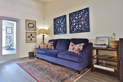 A resident lounge with a sofa, rug, and wall art at The Inverness Apartments in Houston, TX
