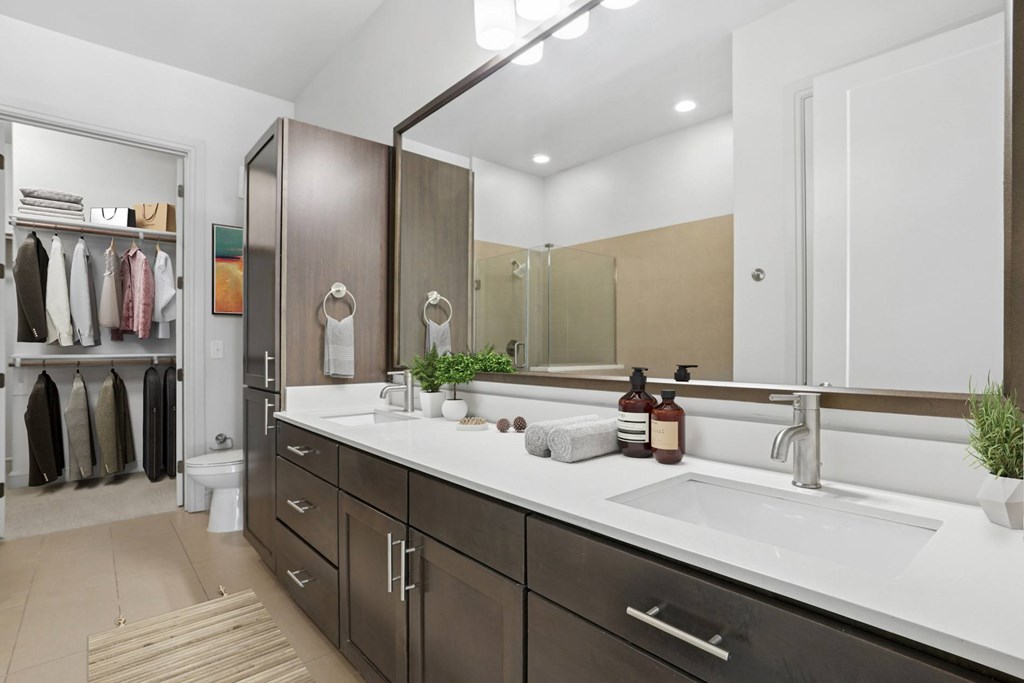 A virtually staged bathroom with a sink, mirror, and a large closet at Knox Heights apartments in Dallas, TX