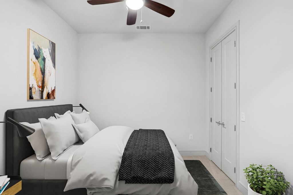 A virtually staged bedroom with a bed, a ceiling fan, and a painting on the wall at Knox Heights apartments in Dallas, TX