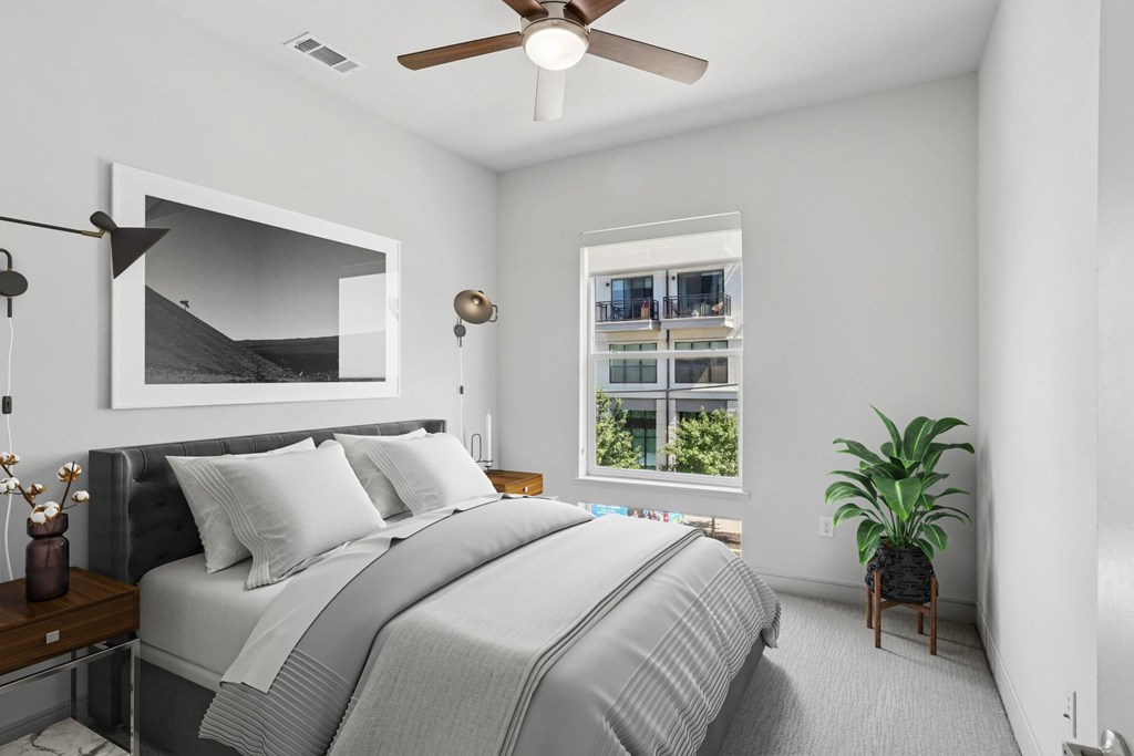 A virtually staged bedroom with a large bed and a ceiling fan at Knox Heights apartments in Dallas, TX