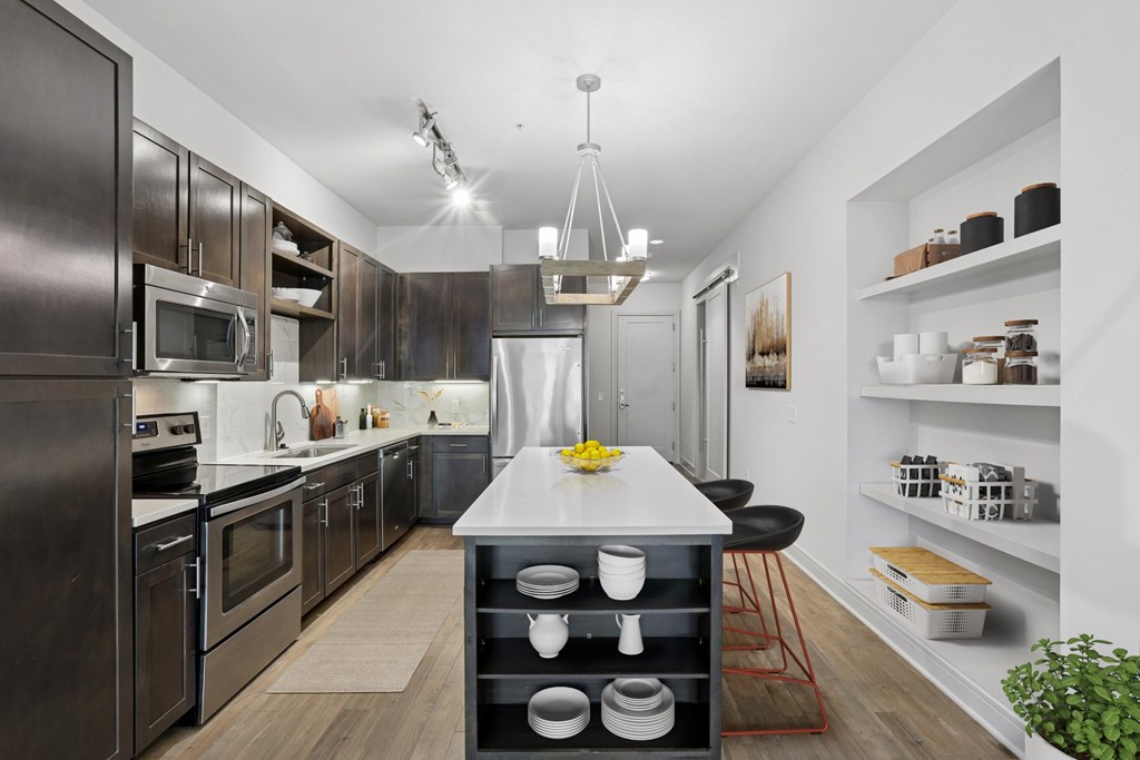 A modern kitchen with dark wood cabinets and a white island at Knox Heights apartments in Dallas, TX