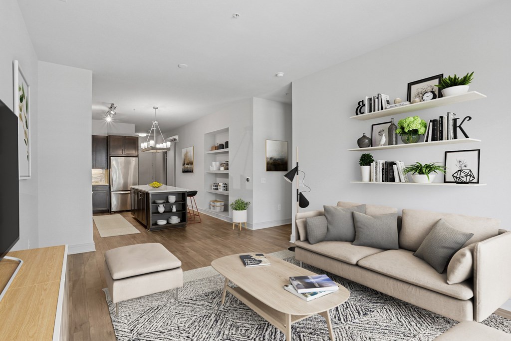 A virtually staged living room with a couch, coffee table, and shelves with plants and picture frames at Knox Heights apartments in Dallas, TX