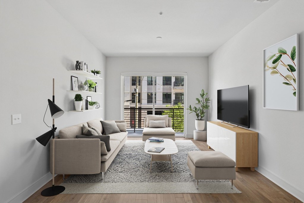 A virtually staged living room with a grey couch, a white coffee table, and a television on a wooden stand at Knox Heights apartments in Dallas, TX