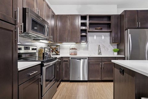 A kitchen with brown cabinets and stainless steel appliances at Knox Heights Apartments in Dallas, TX