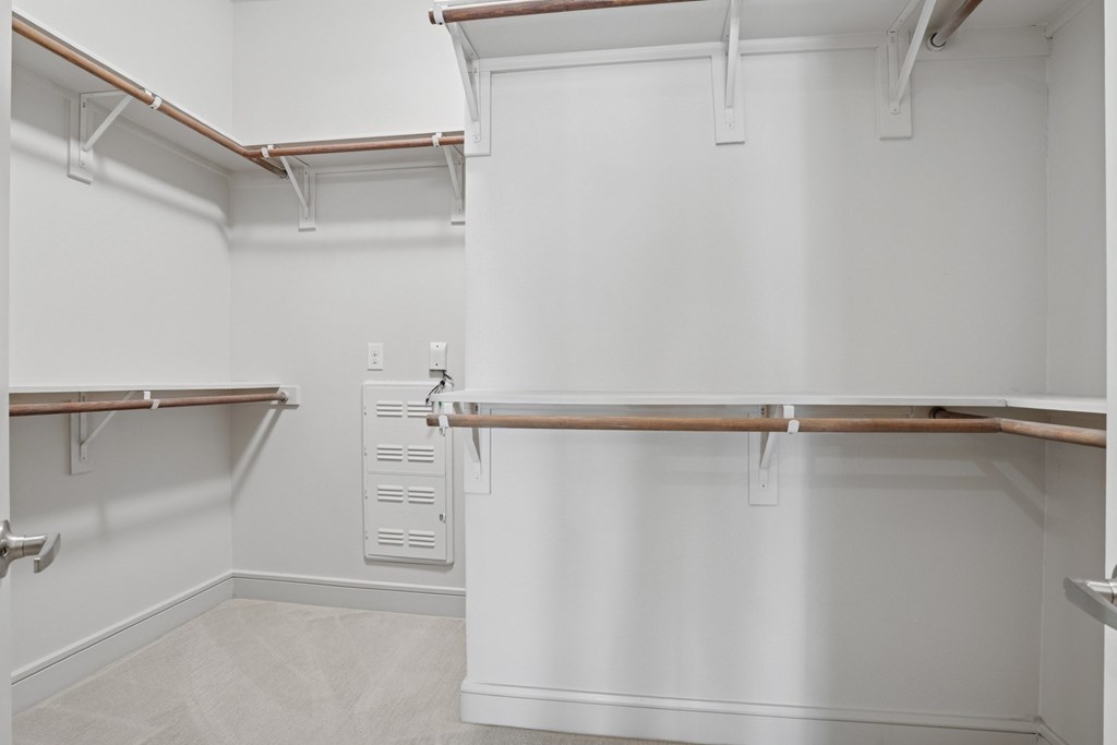 A carpeted walk in closet with white walls and shelves at Knox Heights Apartments in Dallas, TX