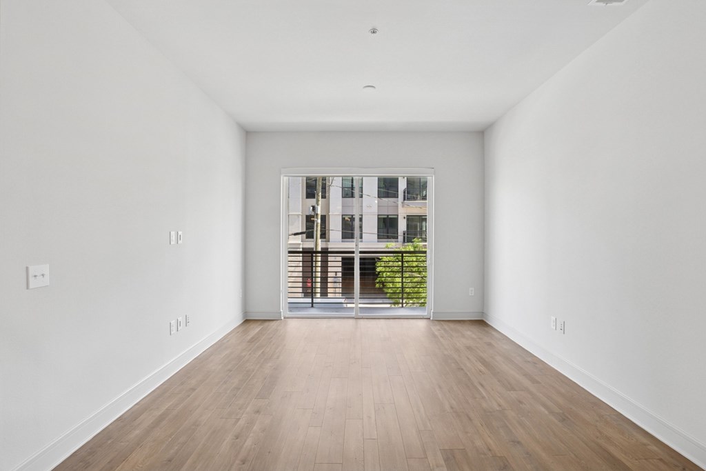 A living and dining room with a large window and wooden flooring in B8 floor plan at Knox Heights in Dallas, TX