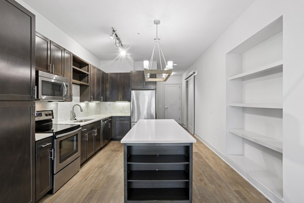A modern kitchen with dark wood cabinets and stainless steel appliances at Knox Heights Apartments in Dallas, TX