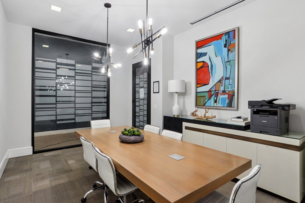 A conference room with a long table, printer, and chairs at Knox Heights Apartments in Dallas, TX