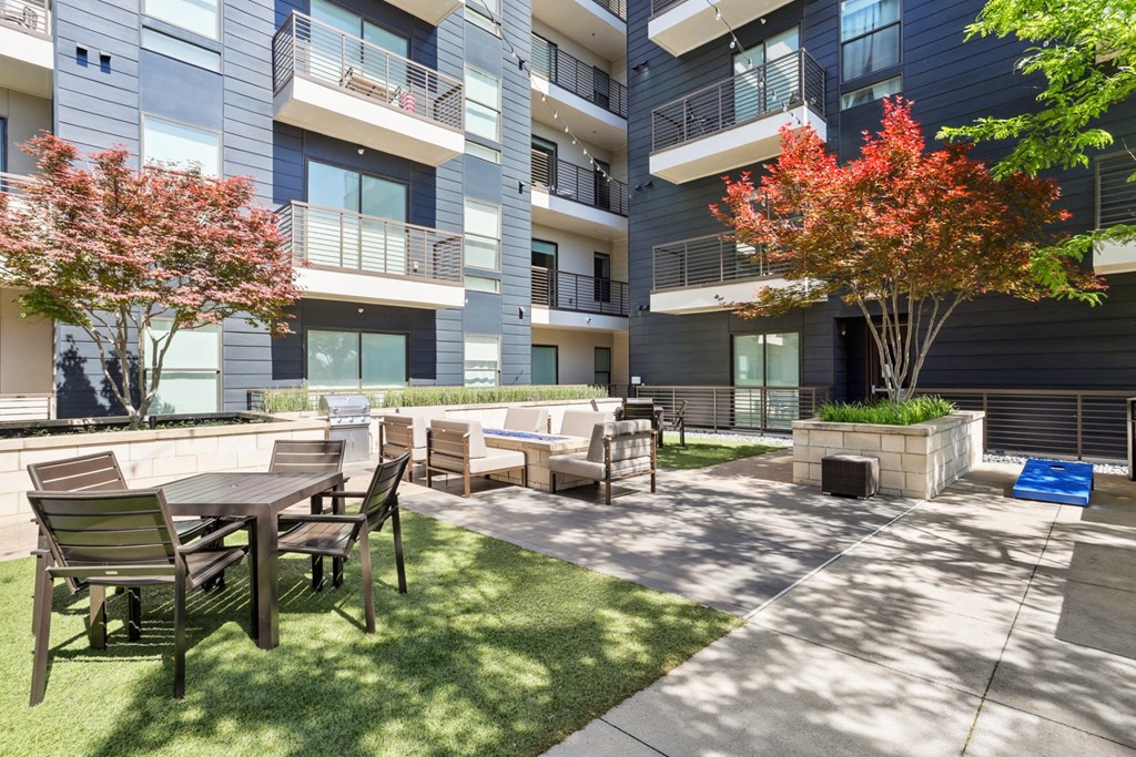 An outdoor courtyard area with a table and chairs is surrounded by apartment buildings at Knox Heights Apartments in Dallas, TX