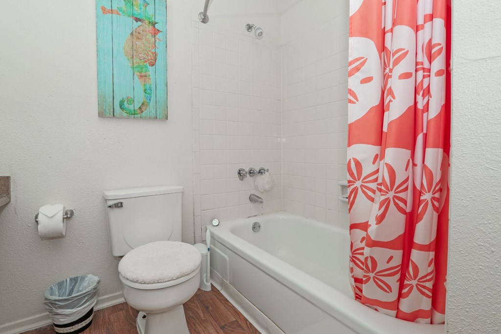 Model bathroom with a white toilet next to a bathtub at Laurel Parc apartments in Shreveport, LA.